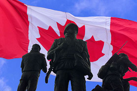 Monument of soldiers with a Canadian flag