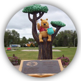 Statue de Winnie l'ourson assis dans un arbre