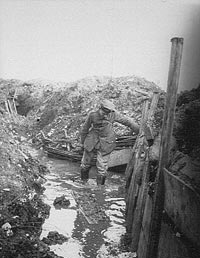 A sapper in a trench with water up to his knees.