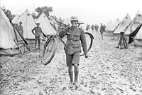 Unable to ride his cycle through the mud caused by a recent storm, a Canadian messenger carries his "horse".