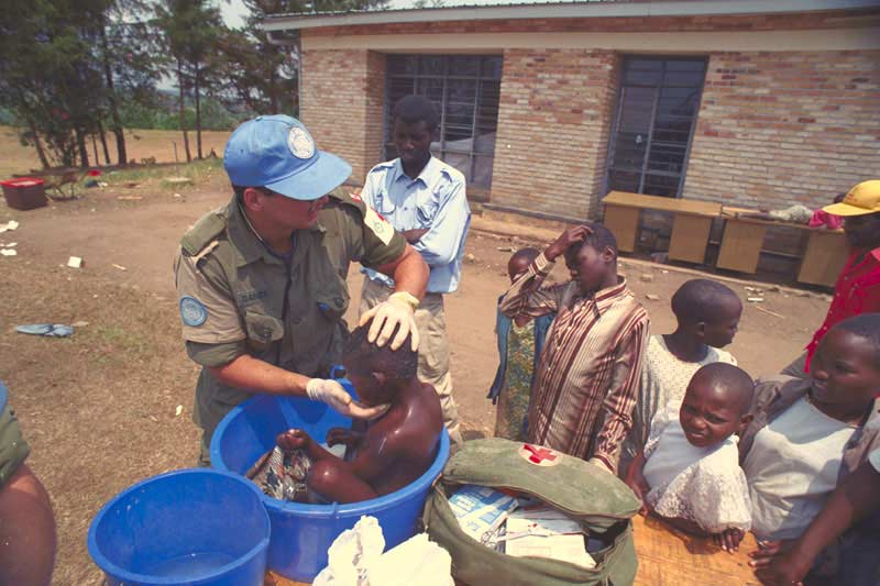 Canadian soldier offering aid to young children in  Rwanda.