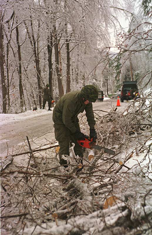 A Canadian Armed Forces member clearing ice-coated trees in rural Quebec in January 1998