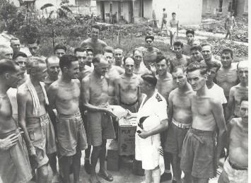 Naval officer with liberated Canadian prisoners of war in Hong Kong after the Japanese surrender.