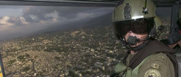 Un membre des Forces armées canadiennes dans un hélicoptère qui monte la garde au-dessus de Port-au-Prince en Haïti.
