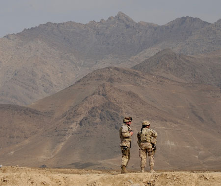 Two soldiers view mountains from firing mound