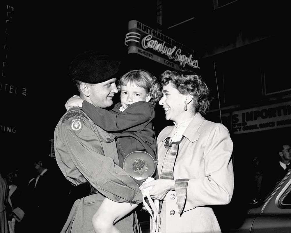 K.A. Pickering of the Lord Strathcona’s Horse  (Royal Canadians) is reunited with his wife and child after serving a year in  Korea, June 1953.