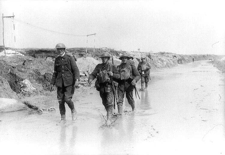 Canadian soldiers wading through a muddy road. April 1917.
