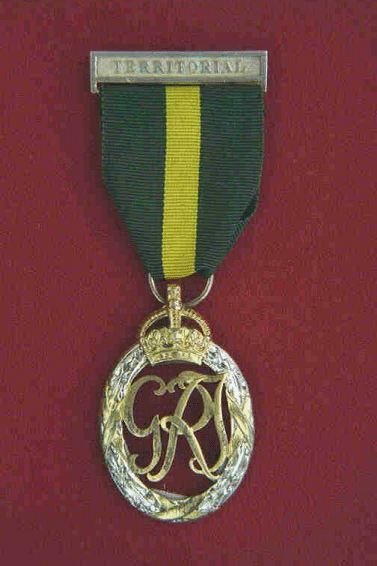 Efficiency Decoration Territorial.  The decoration consists if a oval oak wreath (1.5 x 1.25 inches) in silver tied with gold, with the Royal cypher and crown, also in gold.