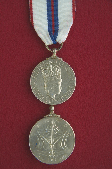 Queen Elizabeth II Silver Jubilee Medal (1977).  The circular silver medal, 1.25 inches (32 mm) in diameter, has a thin, smooth raised rim.