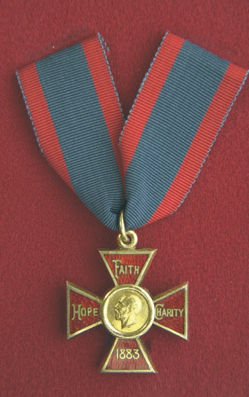 Royal Red Cross Class 1.  A cross, 1.375 inches wide, enamelled red, and edged with gold, with a circular medallion at its centre.