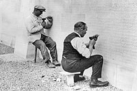 Two men cutting names into the face of the Vimy Memorial.